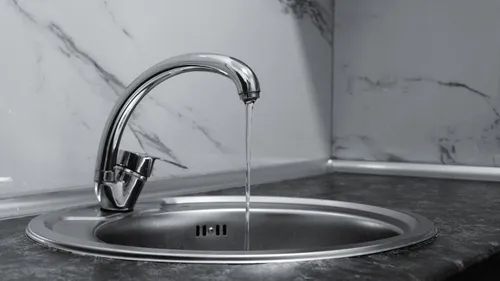 Chrome kitchen faucet running into a stainless-steel sink.