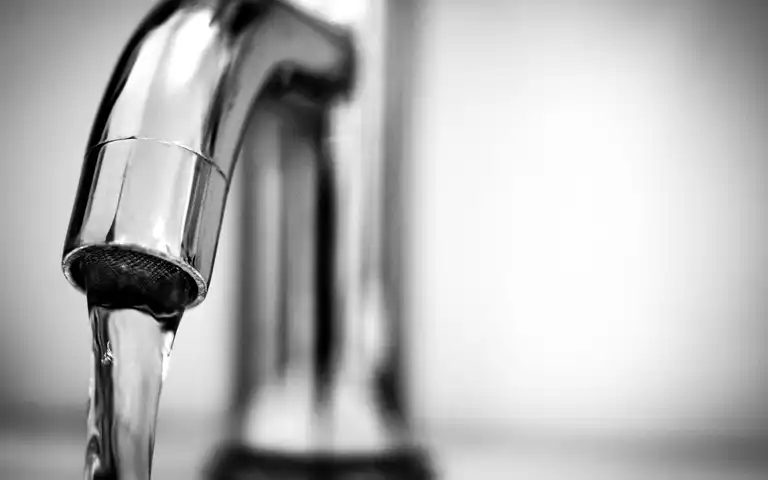 A close-up shows clear water running from a stainless-steel faucet.