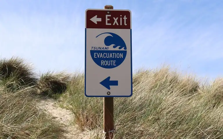 A tsunami evacuation route sign beside a coastal path in Oregon.
