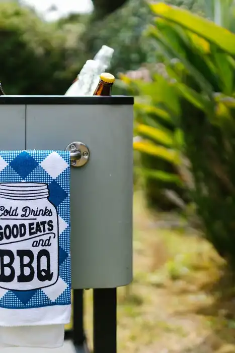 An outdoor cooler holds bottled drinks beside a garden.
