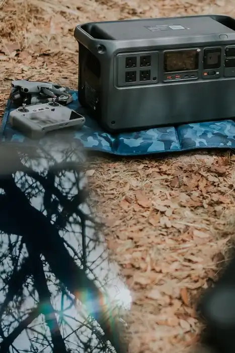 A portable power station on a mat beside a solar panel outdoors.