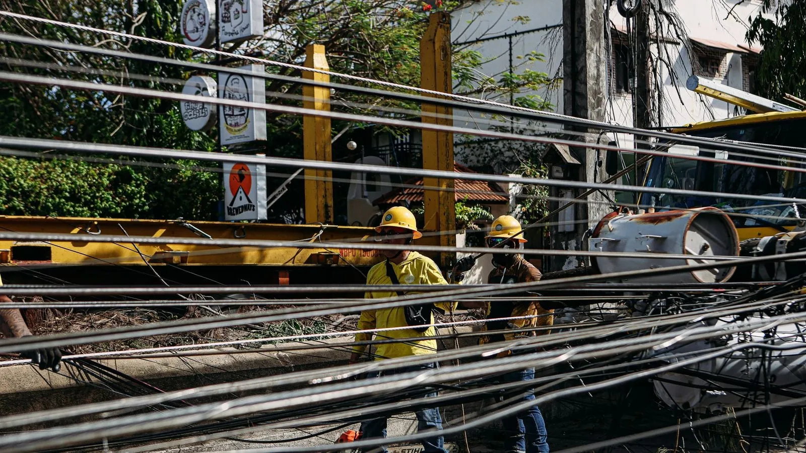 Utility workers in hard hats repairing tangled power lines outdoors.