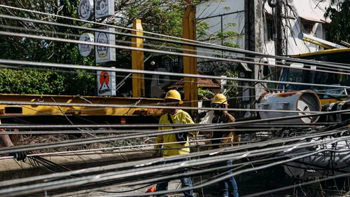 Utility workers in hard hats repairing tangled power lines outdoors.