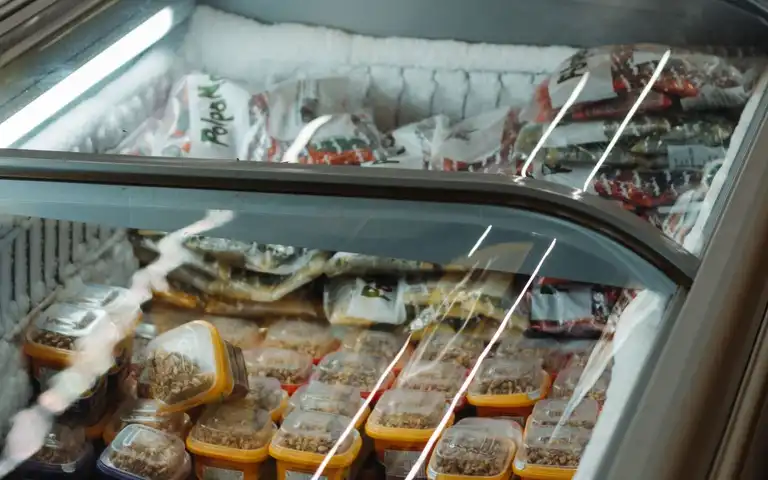Packaged frozen foods are displayed in a commercial chest freezer.