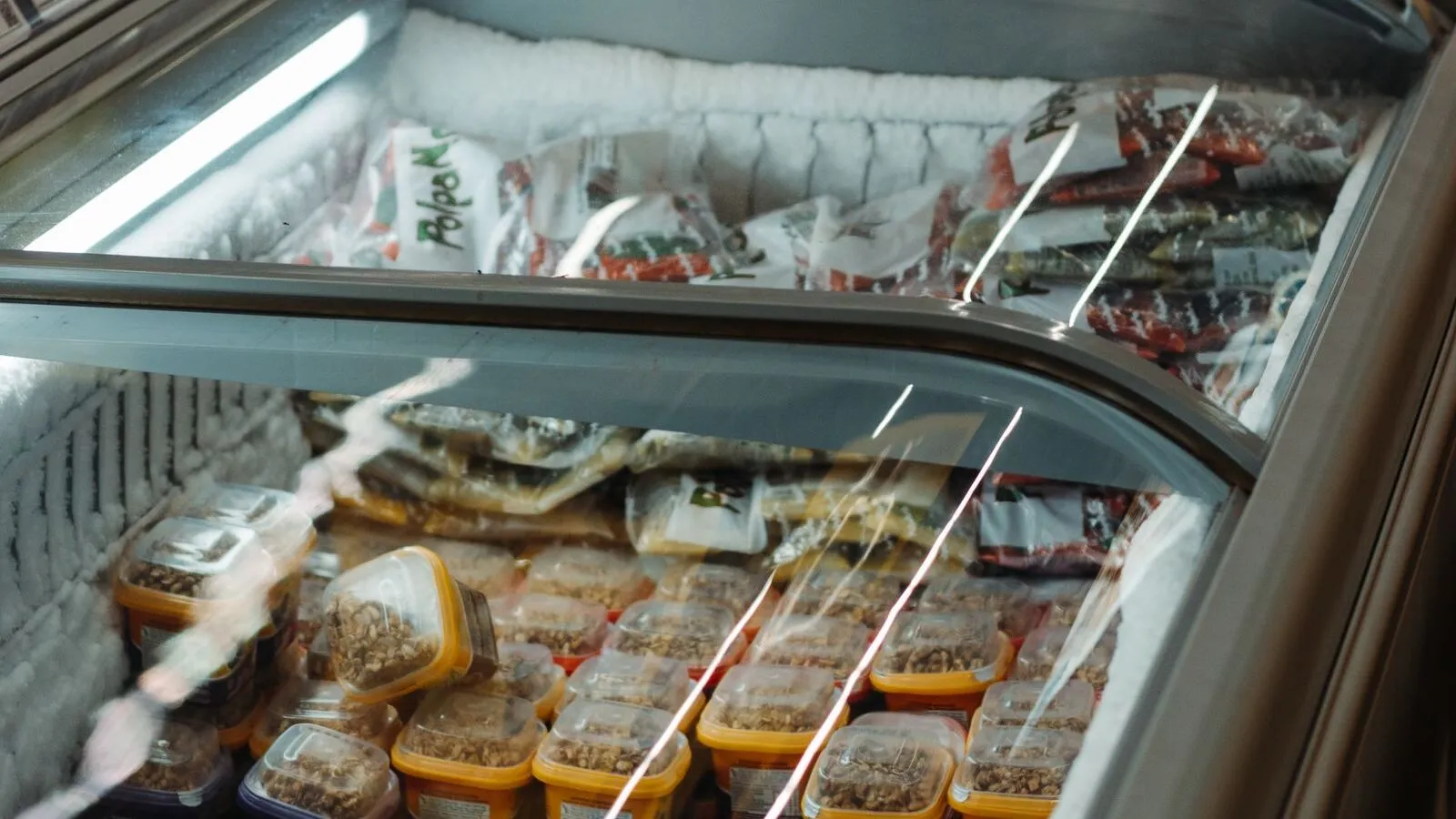 Packaged frozen foods are displayed in a commercial chest freezer.