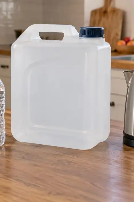 Bottled water, an empty water container, an electric kettle, and a portable filter arranged separately on a kitchen counter