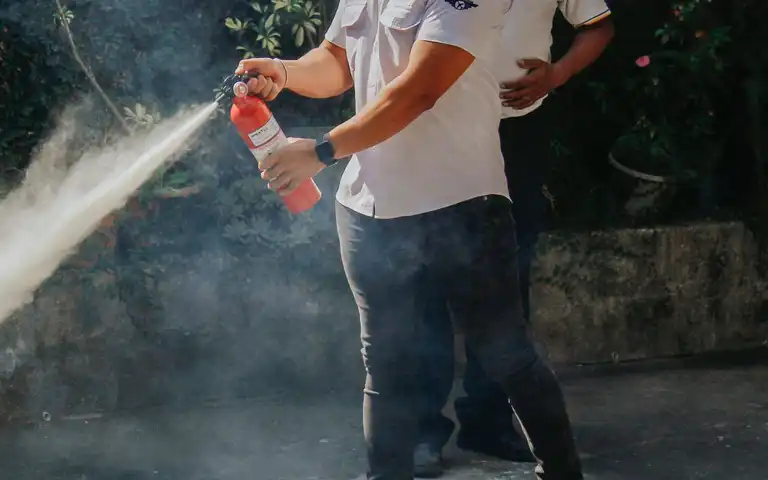 Two men demonstrate a fire extinguisher outdoors
