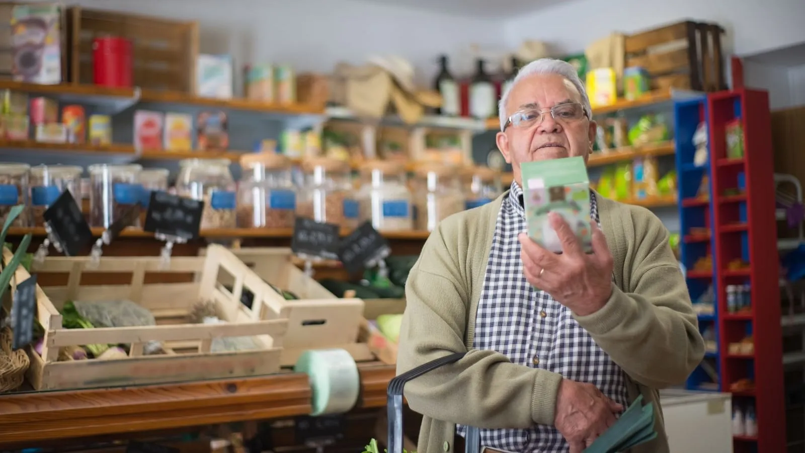 Older shopper looking at a packaged grocery product.