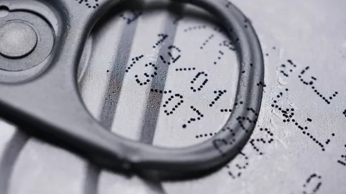 Close-up of a drink-can lid with a printed expiration date.