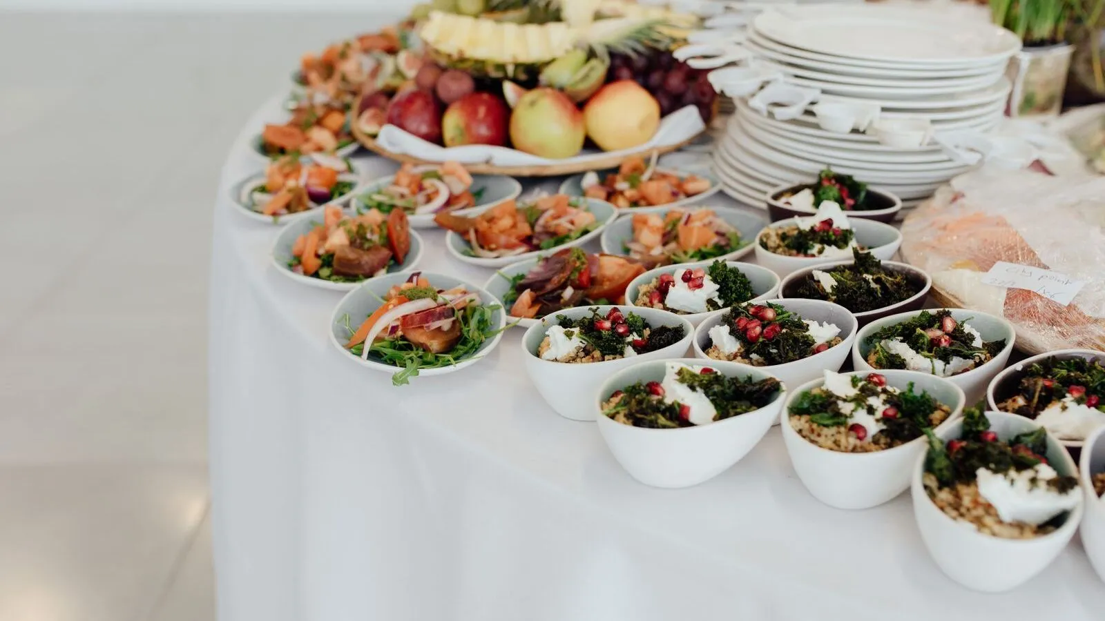 Small dishes of prepared food and fruit are arranged on a buffet table.