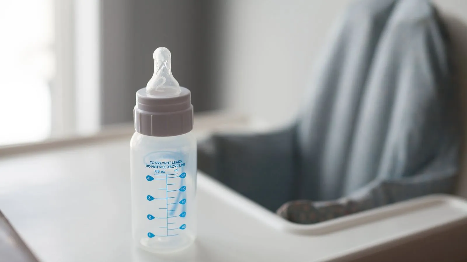 Baby bottle resting on a high-chair tray.