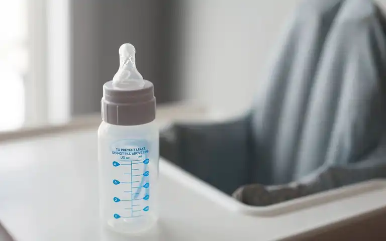 Baby bottle resting on a high-chair tray.