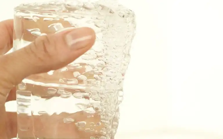 Hand holding a glass filled with water.