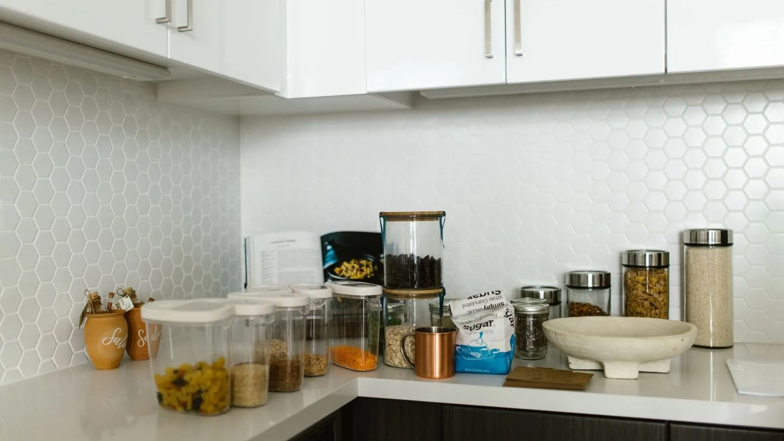 Food storage containers and jars sit on a kitchen counter.