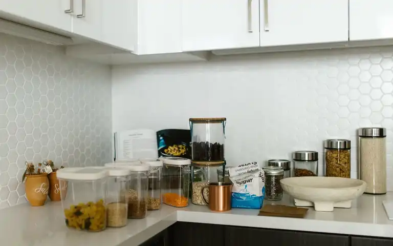 Food storage containers and jars sit on a kitchen counter.