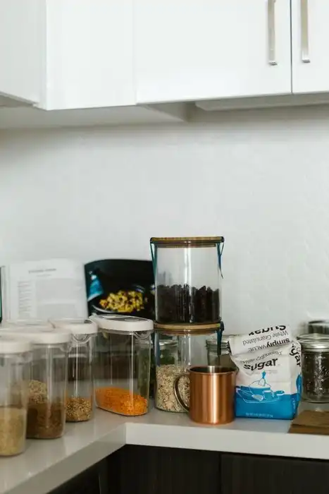 Food storage containers and jars sit on a kitchen counter.