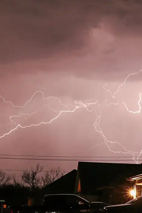 Lightning flashes over a residential neighborhood at night.