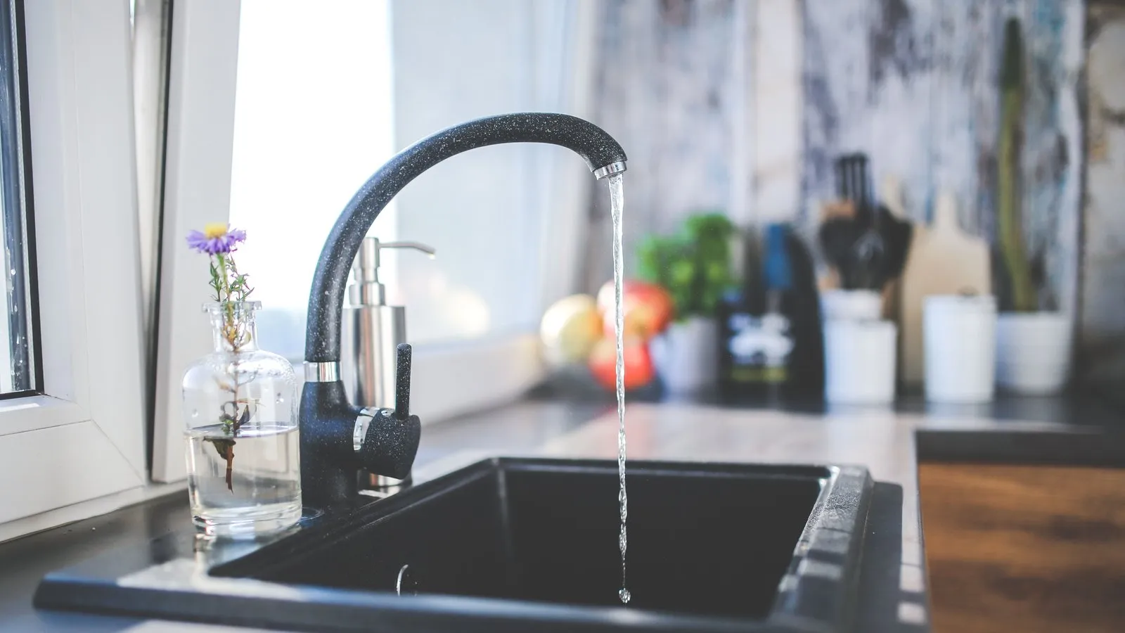 A kitchen faucet sends a stream of water into a sink.