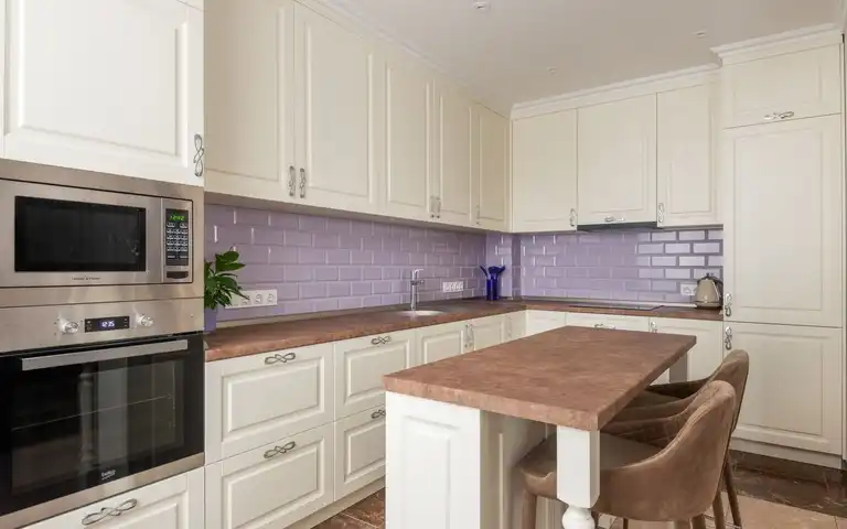 A built-in microwave above an oven in a white kitchen.
