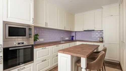 A built-in microwave above an oven in a white kitchen.