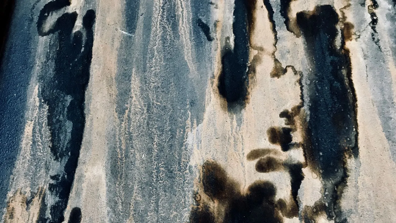 Dark mildew stains and mottled discoloration on a weathered wall surface.