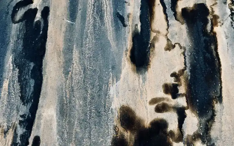 Dark mildew stains and mottled discoloration on a weathered wall surface.