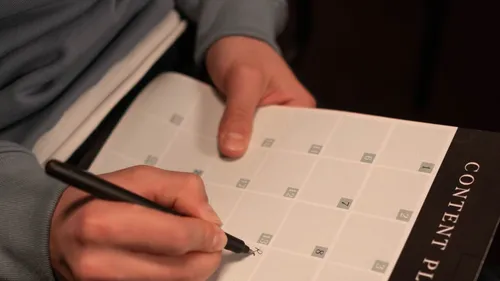 A person writing notes in an open planner.