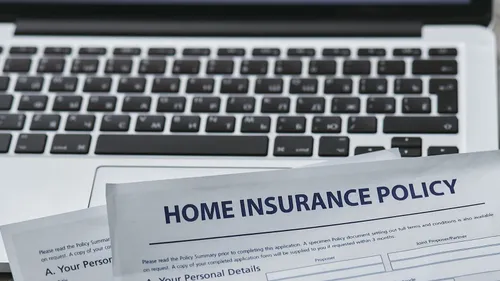 Home insurance paperwork beside a laptop and keyboard.