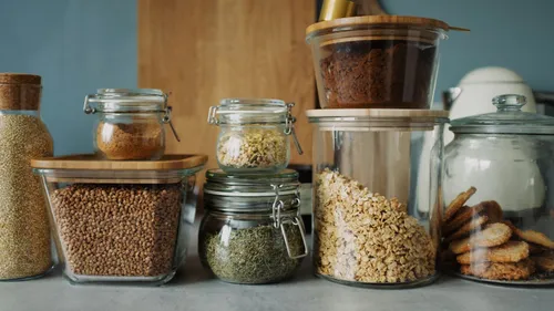 Glass jars of grains, dry goods, and cookies line a pantry counter.