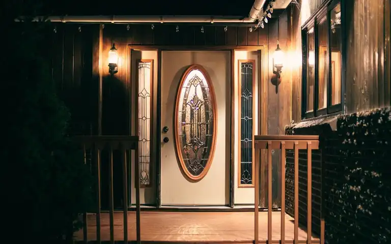 A house entrance and porch are lit at night.