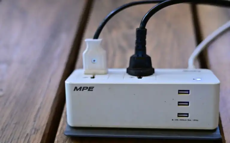 Power strip with two connected plugs and three USB ports on a wooden surface.