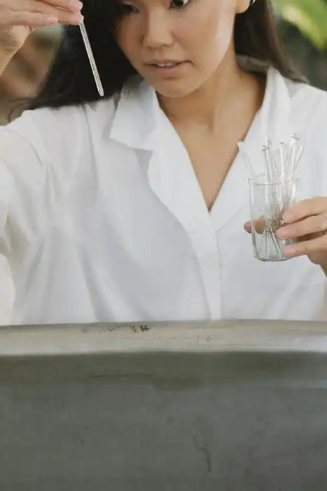 A person in a white coat examines a small sample vial.