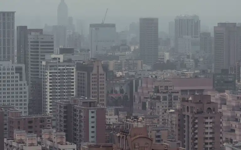 A hazy urban skyline with tall buildings in the distance.