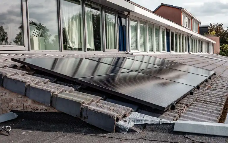Rows of rooftop solar panels beside a long line of windows.
