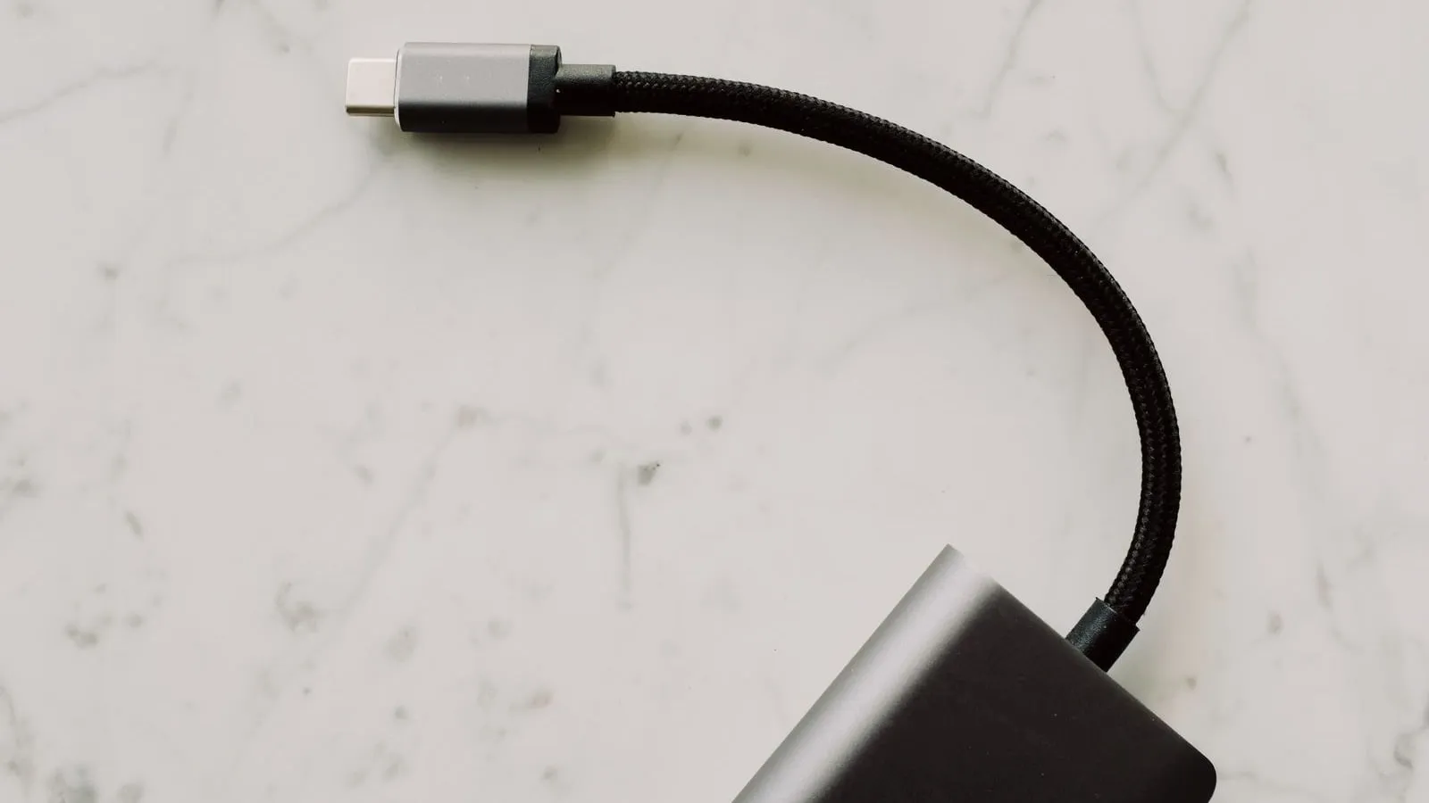 A short braided USB-C cable attached to an adapter on a white surface.