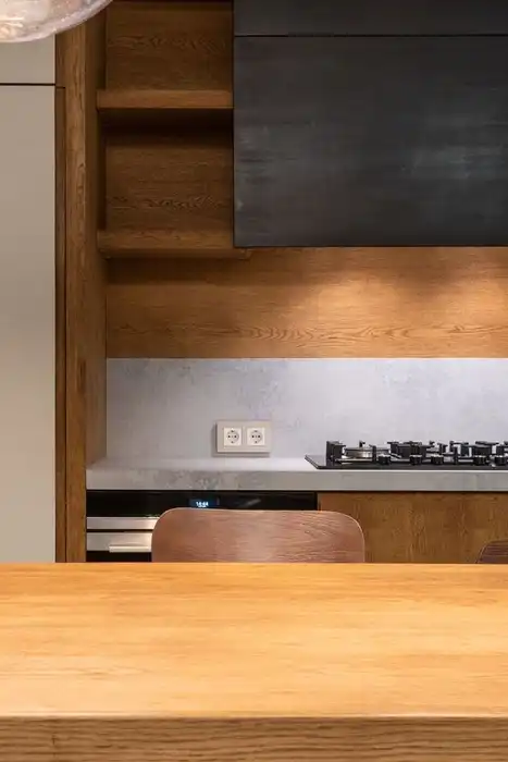 A modern kitchen with a gas cooktop is seen beyond a wooden counter.