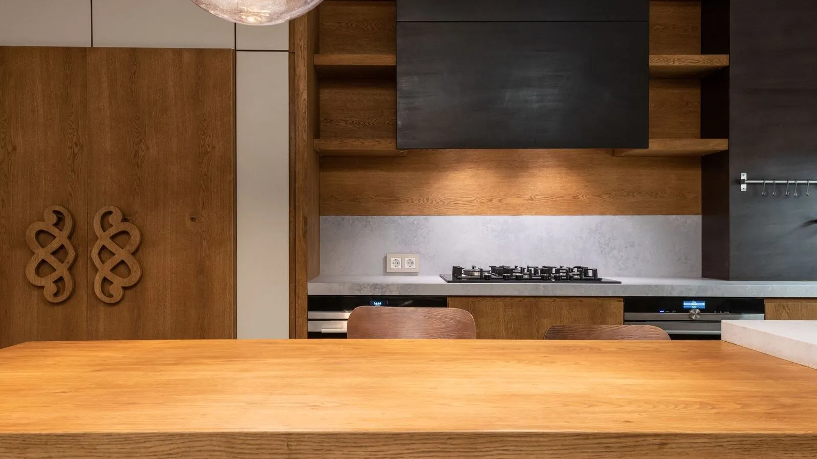 A modern kitchen with a gas cooktop is seen beyond a wooden counter.