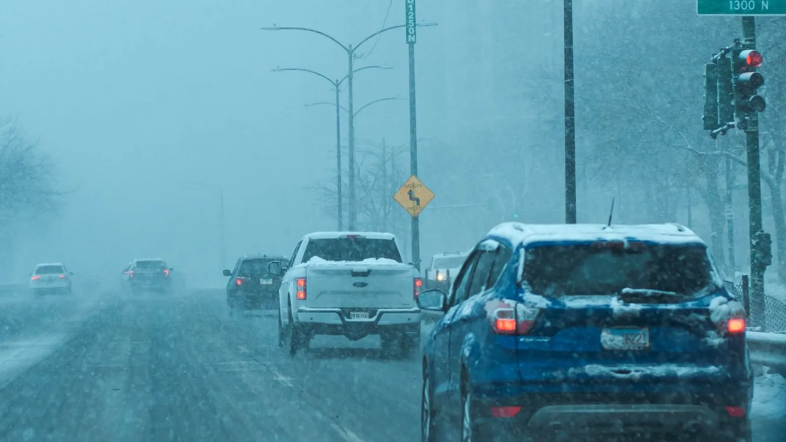 Cars traveling on a snow-covered urban street.